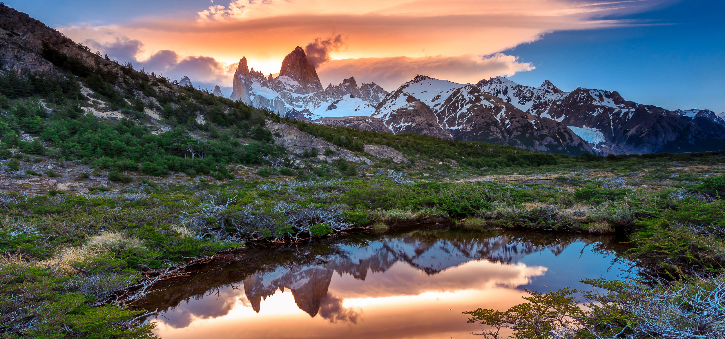 A sunset view of Mt Fitz Roy with a reflection in a grassy pond in Los Glaciares National Park, Argentina