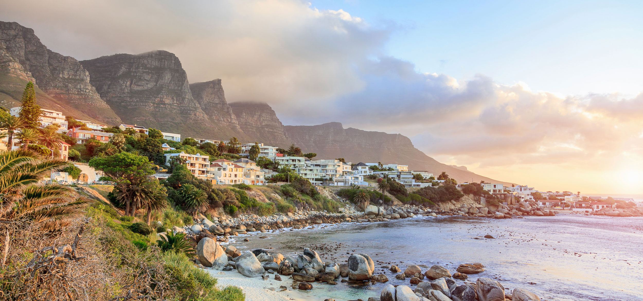 An aerial view of Cape Town Camps Bay with houses, ocean, and mountains in the background in Cape Town, South Africa