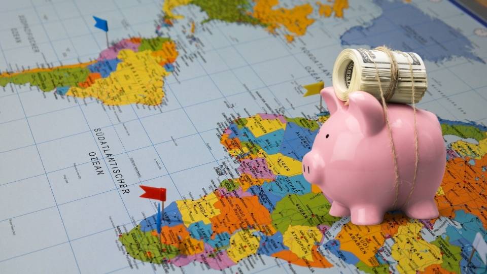 Start saving-A piggy bank with a roll of bills over a world map